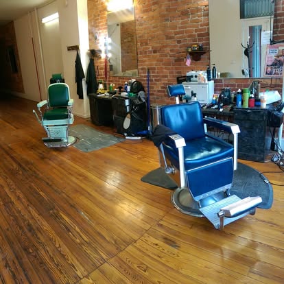 Vintage green and blue barber chairs on the shop’s wood floor